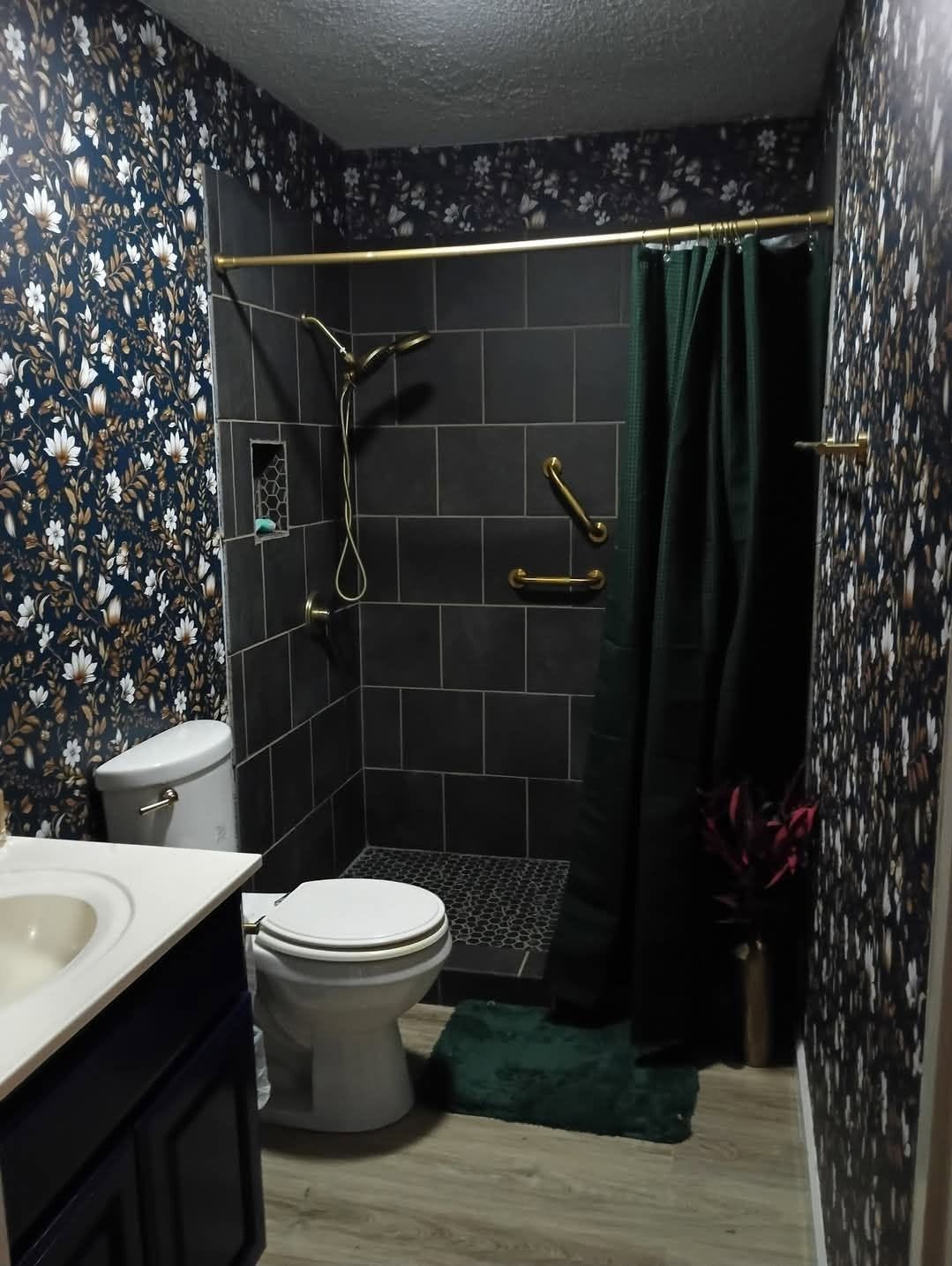 Remodeled bathroom with dark tiled walk-in shower and gold fixtures